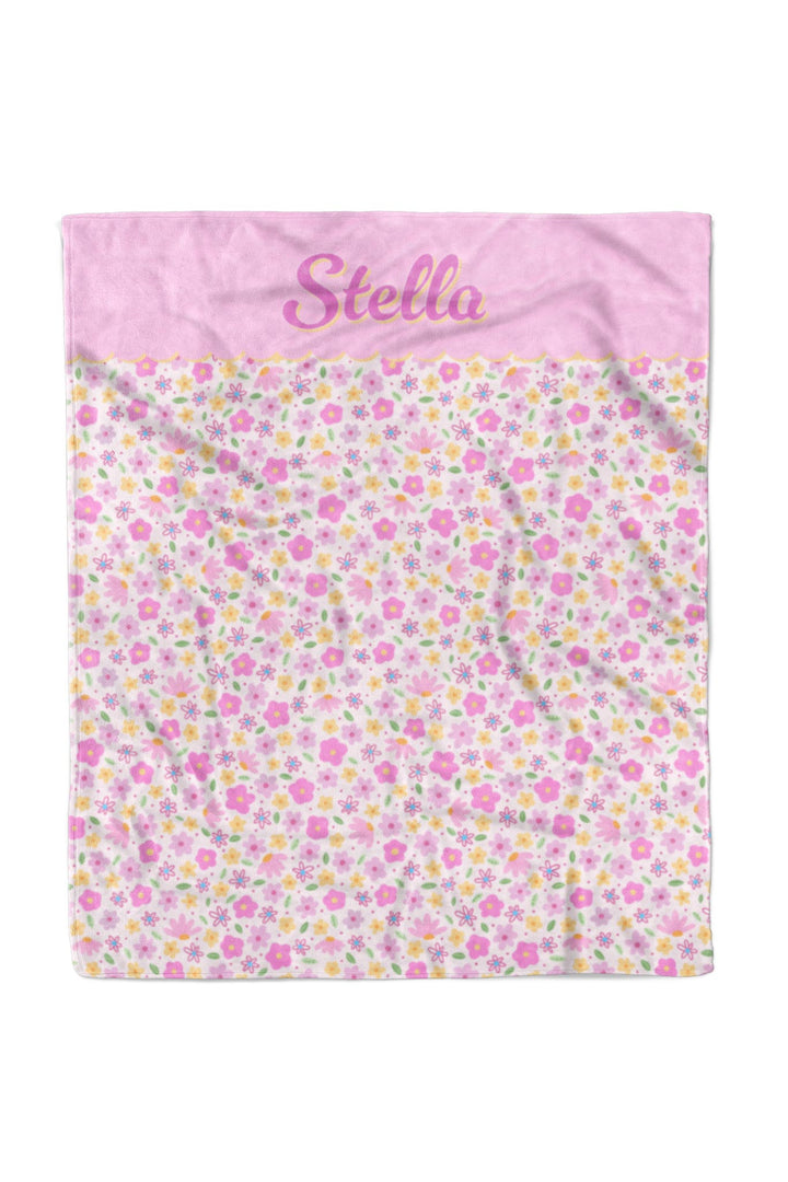 Personalized pet blanket in Scattered Blooms print with solid pink top panel featuring pet name in script, and pink, purple, and yellow floral pattern on white