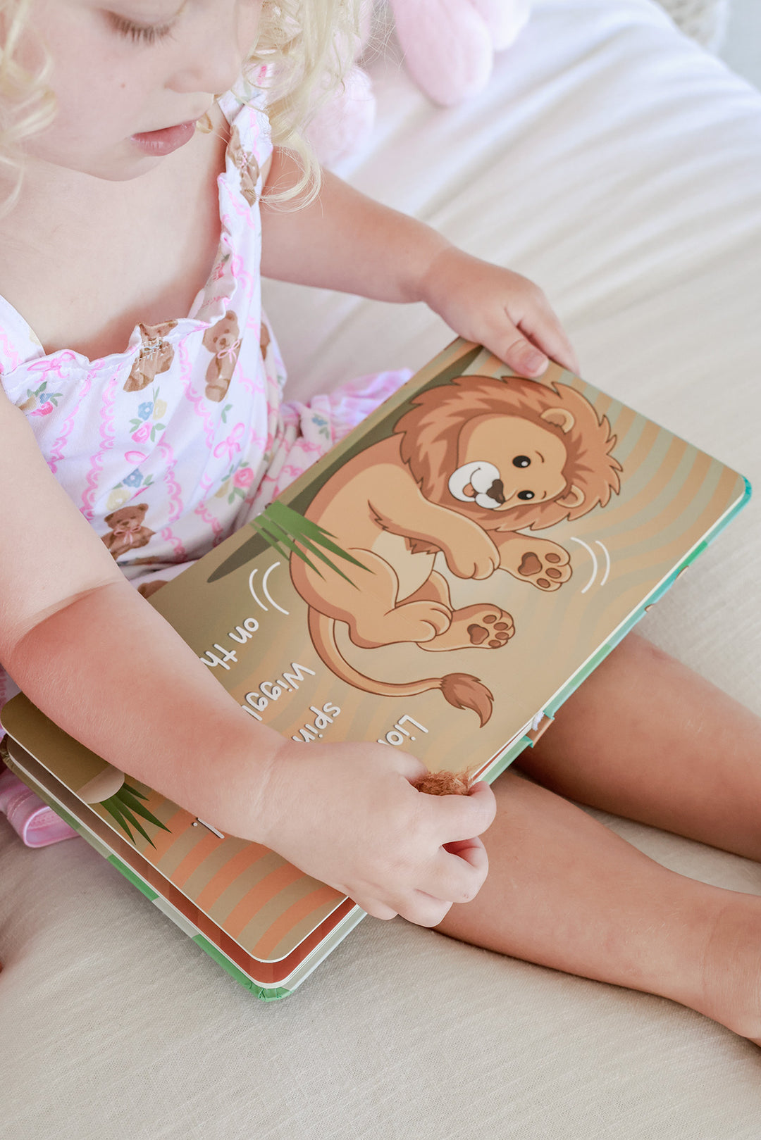 Young child reading inside pages of Little Lion's Roooar Cuddle Plush Friends Story Book showing lion character illustration