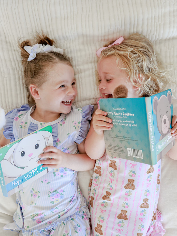 Three young girls lying on a bed reading Cuddle Plush Friends Story Books by Parker Puppy, Hop HOP Bunny, and Rory Lion