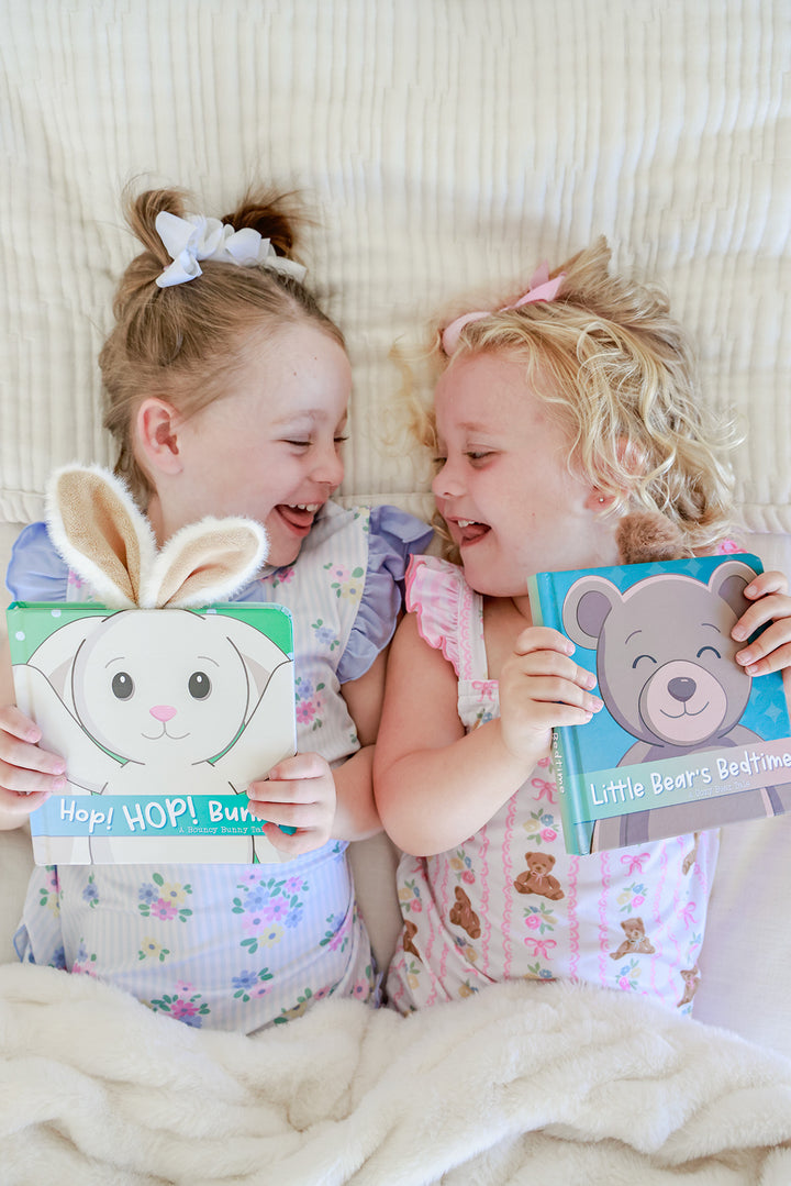 Two young girls lying on a bed laughing while holding Hop HOP Bunny and Little Bear's Bedtime Cuddle Plush Friends Story Books