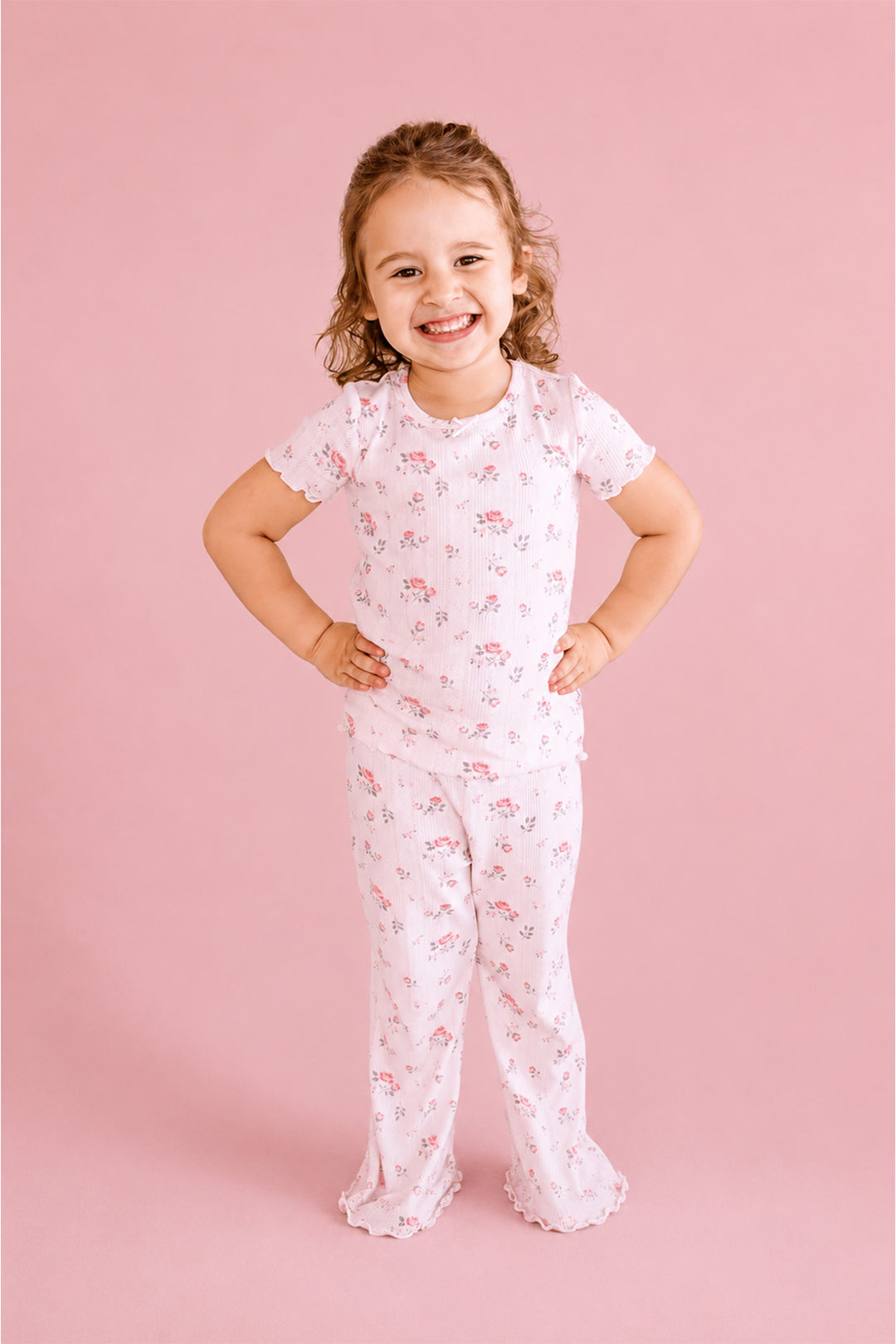 Caden Lane Rose Garden pajama set, smiling toddler girl in white floral pointelle pajamas, standing