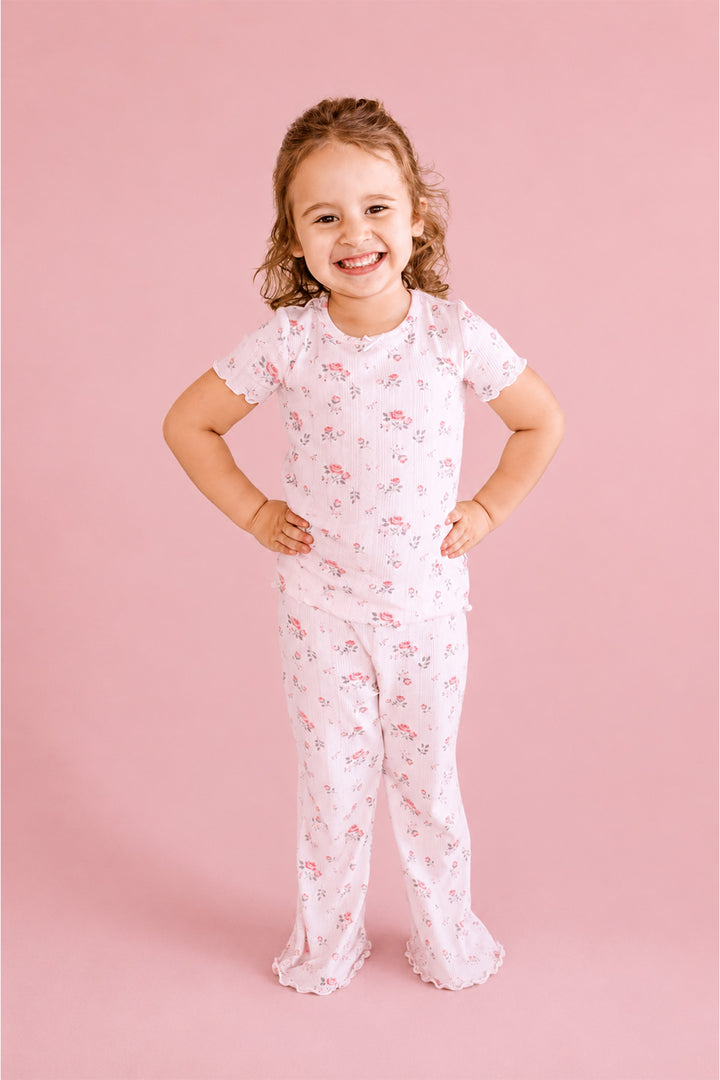 Caden Lane Rose Garden pajama set, smiling toddler girl in white floral pointelle pajamas, standing