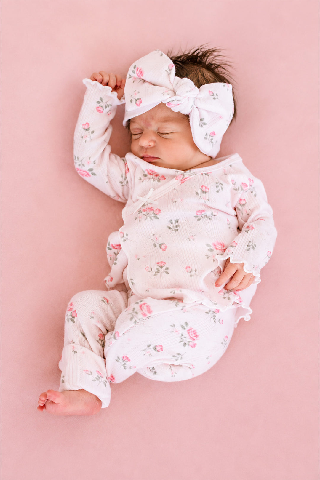 Caden Lane Rose Garden newborn take-home outfit, sleeping baby in pink floral footie and matching bow headband