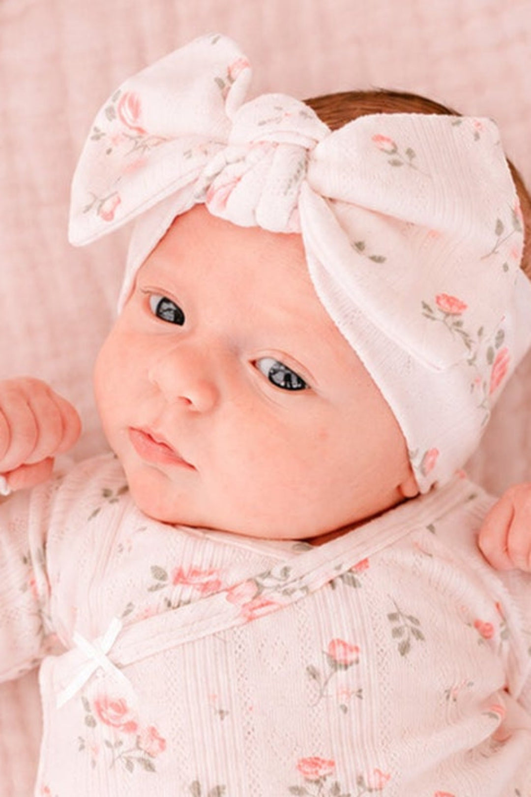 Caden Lane Rose Garden newborn outfit, close-up of baby wearing pink floral gown and matching bow headband