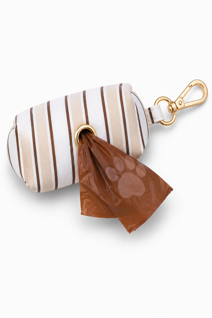 Pet waste bag holder in Biscuit Stripe pattern with a brown paw-print waste bag being dispensed from the bottom, gold carabiner clip attached at top