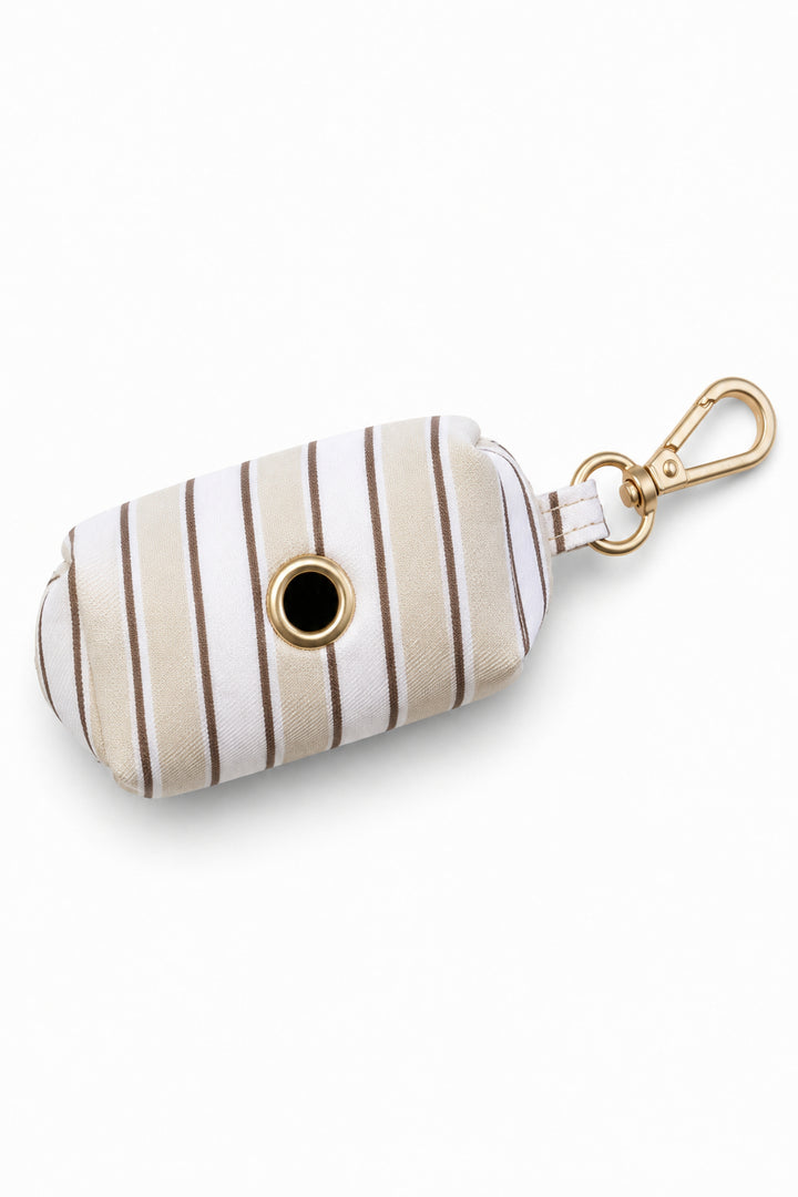 Front view of Biscuit Stripe pet waste bag holder showing the circular dispensing opening at the center, with a gold carabiner clip at the top