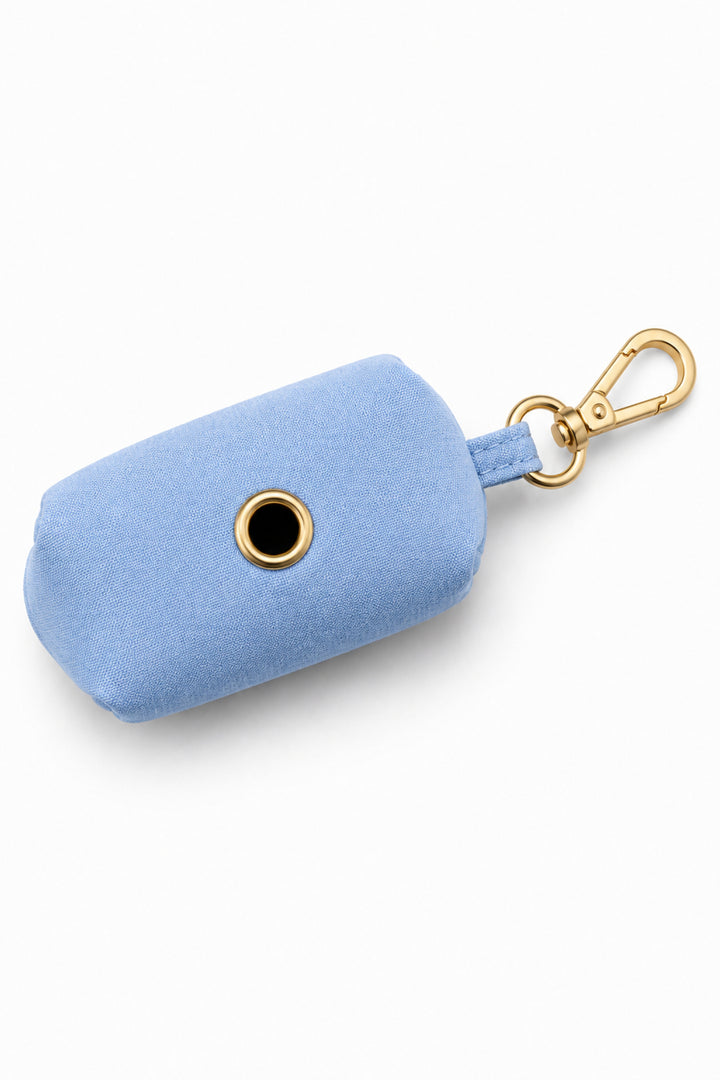 Bottom view of Caden Lane denim days light blue waste bag holder showing dispensing opening with gold button and carabiner clip