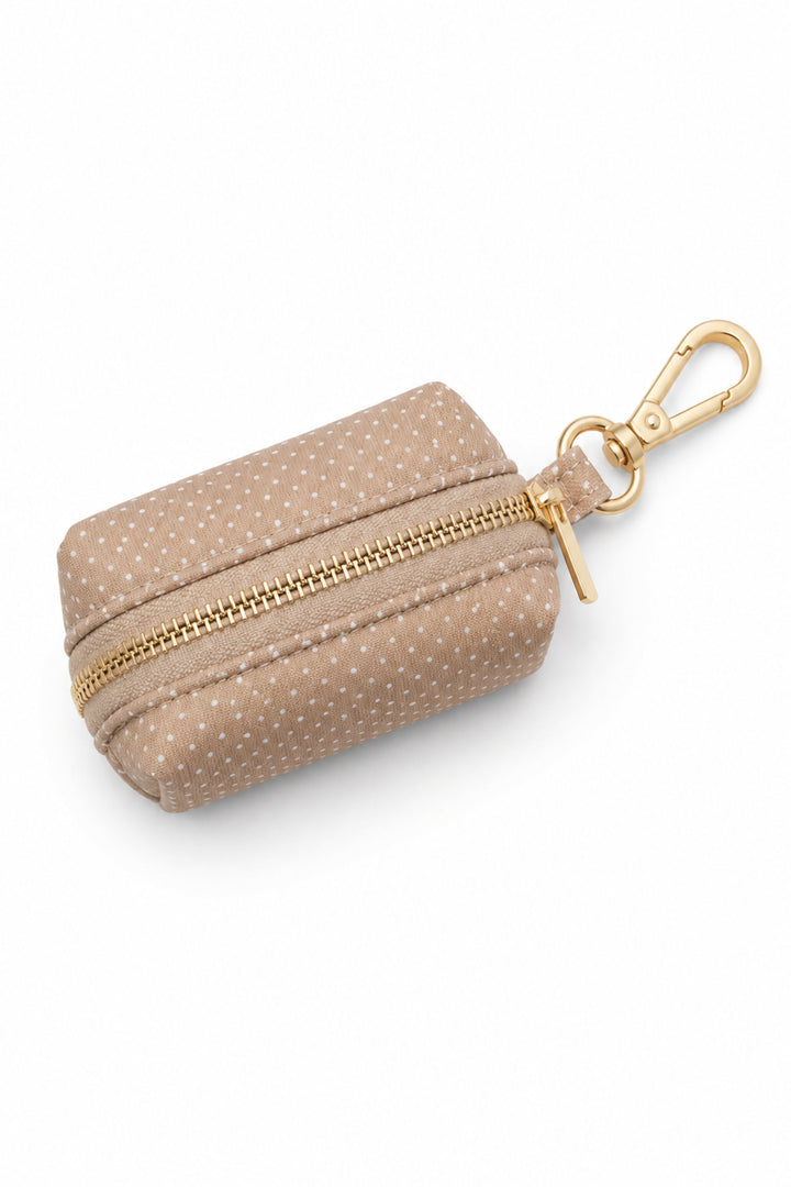 Latte brown polka dot pet waste bag holder with gold zipper and gold carabiner clip on a white background