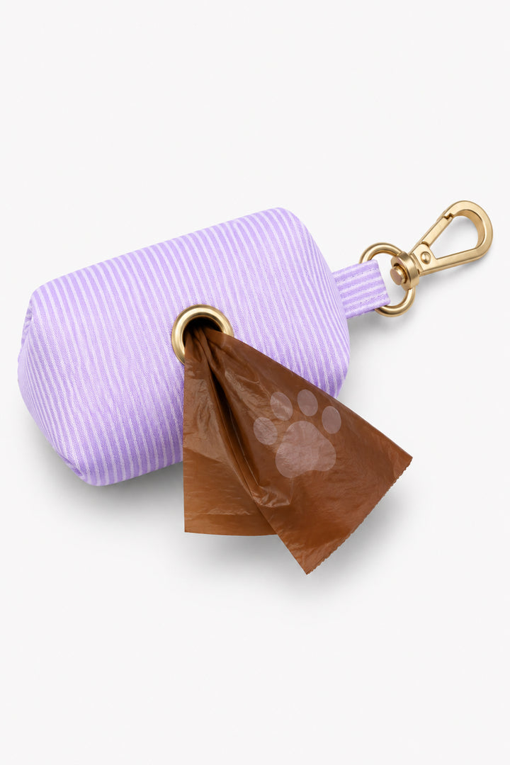 Lavender woven waste bag holder with a paw-print brown bag being dispensed from the bottom opening, with gold carabiner clip