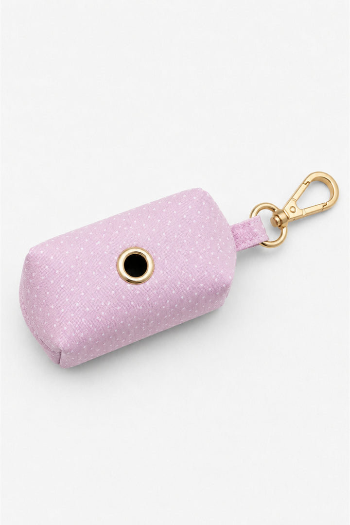 Bottom view of pink polka dot pet waste bag holder showing the circular dispensing opening with gold metal grommet and gold carabiner clip