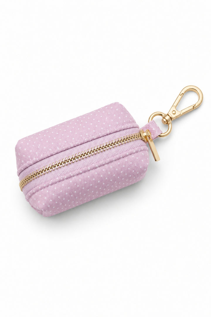 Pink polka dot pet waste bag holder with gold zipper closure and gold carabiner clip for leash attachment