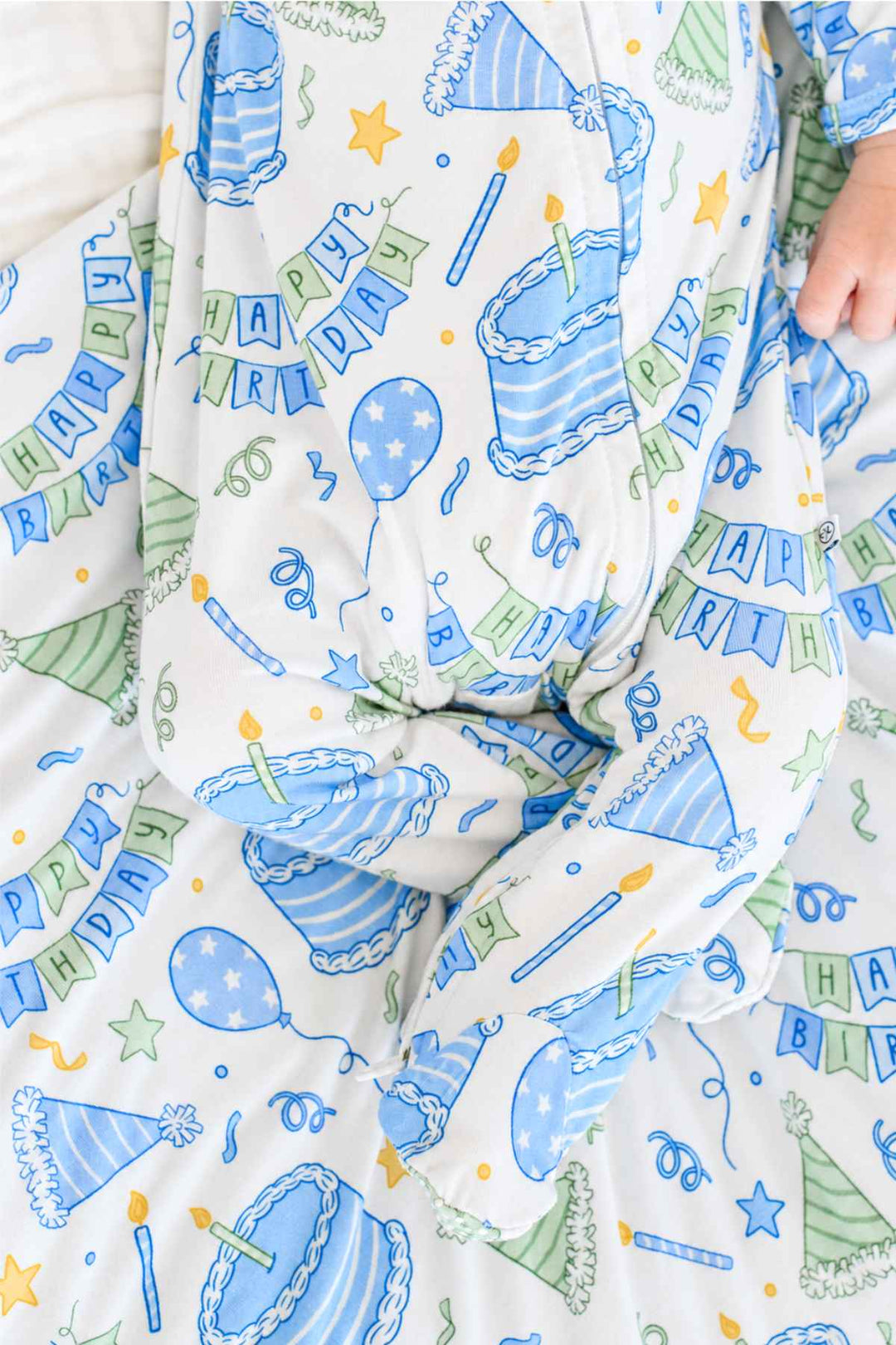 Close-up of the Caden Lane Birthday Bash Blue newborn knotted gown featuring birthday cakes, balloons, party hats and banners.