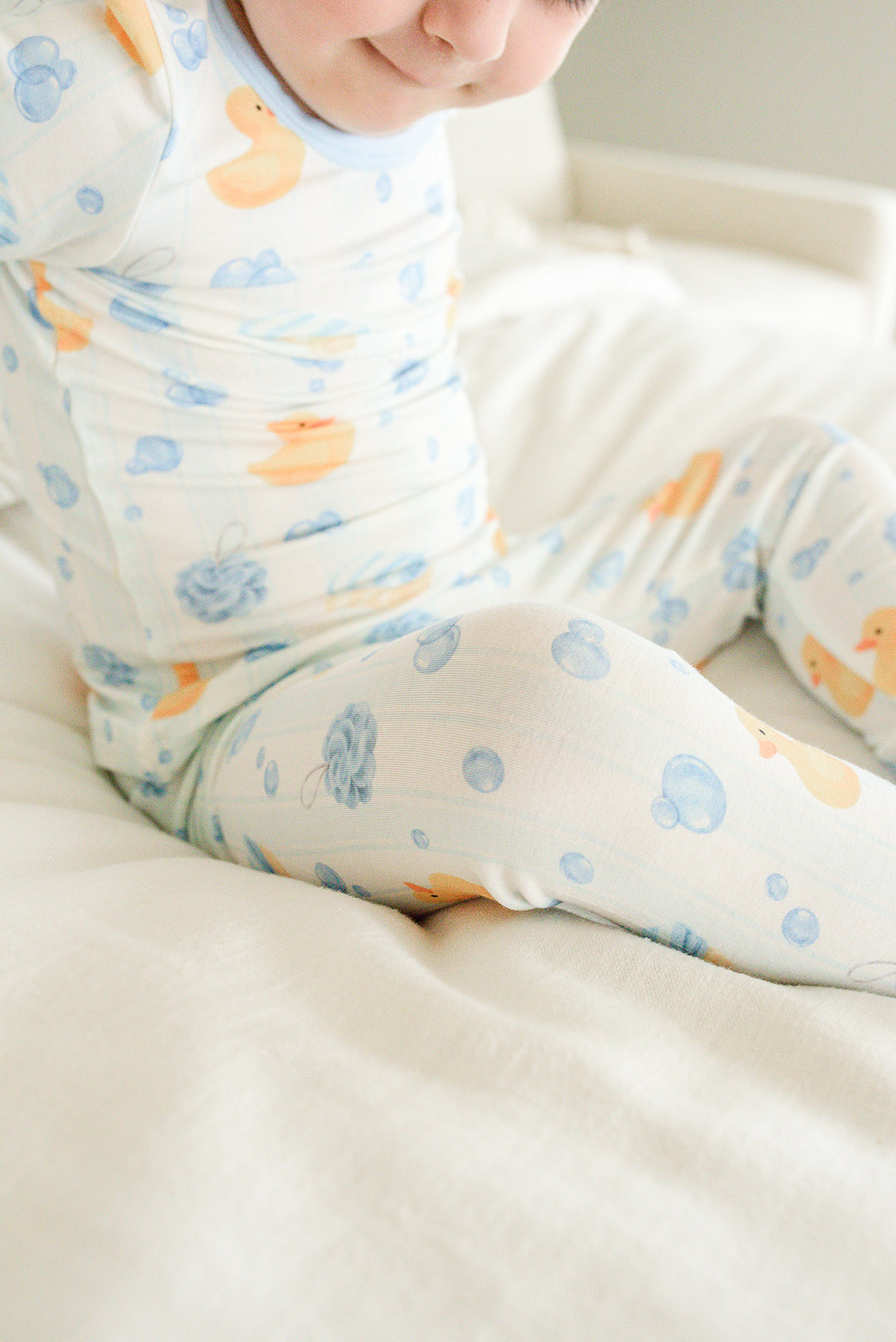 Close-up of baby wearing blue Bubble Duckies two-piece bamboo pajamas showing yellow rubber duck and blue bubble print fabric detail