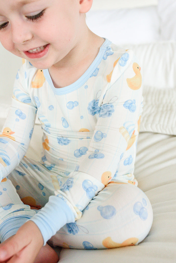 Close-up of boy wearing blue Bubble Duckies two-piece bamboo pajama top showing yellow rubber duck and blue bubble print