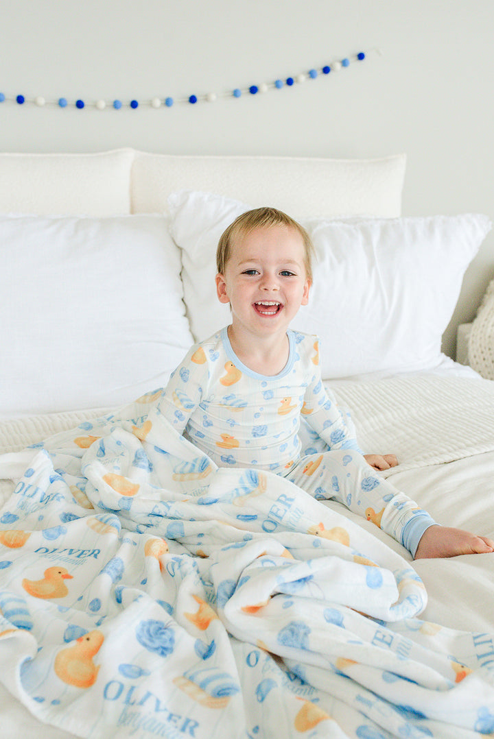 Happy boy wrapped in blue Bubble Duckies personalized blanket with rubber duck print and custom name