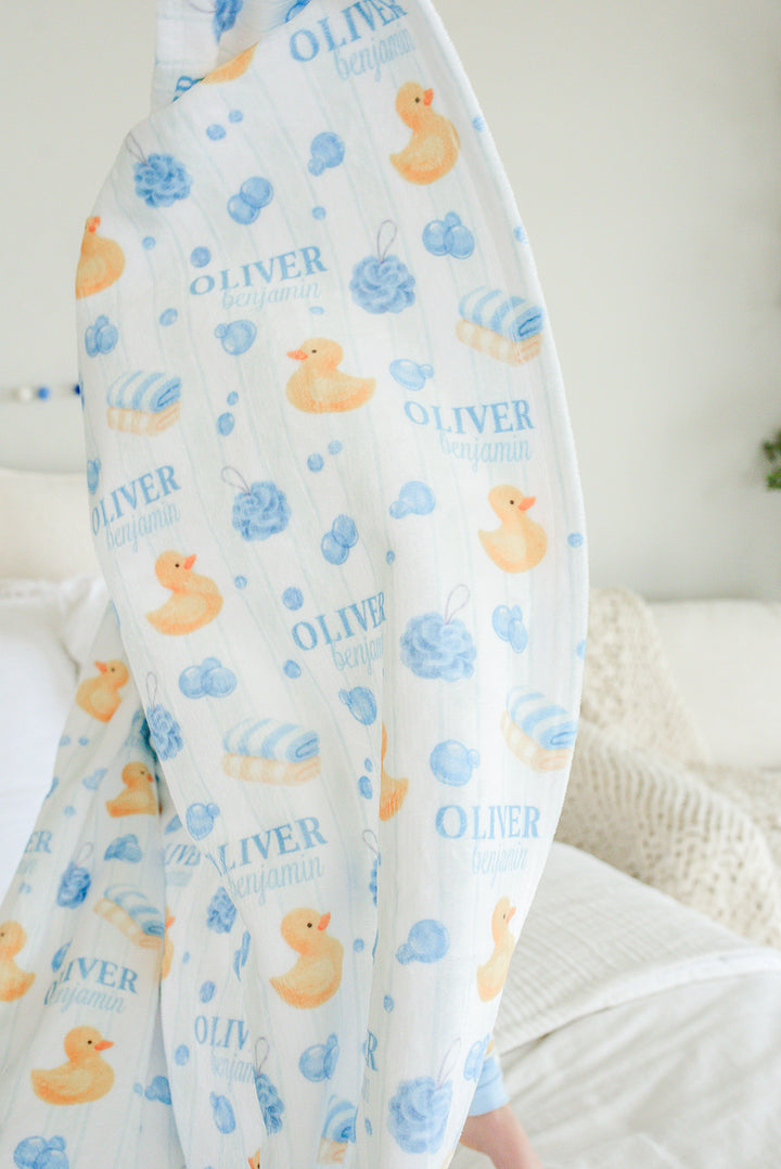 Toddler boy cuddled in blue Bubble Duckies personalized blanket with yellow rubber duck and blue bubble print