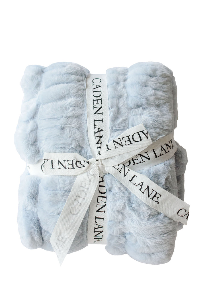 Folded double-ruched faux fur baby blanket in ice blue, tied with a Caden Lane ribbon