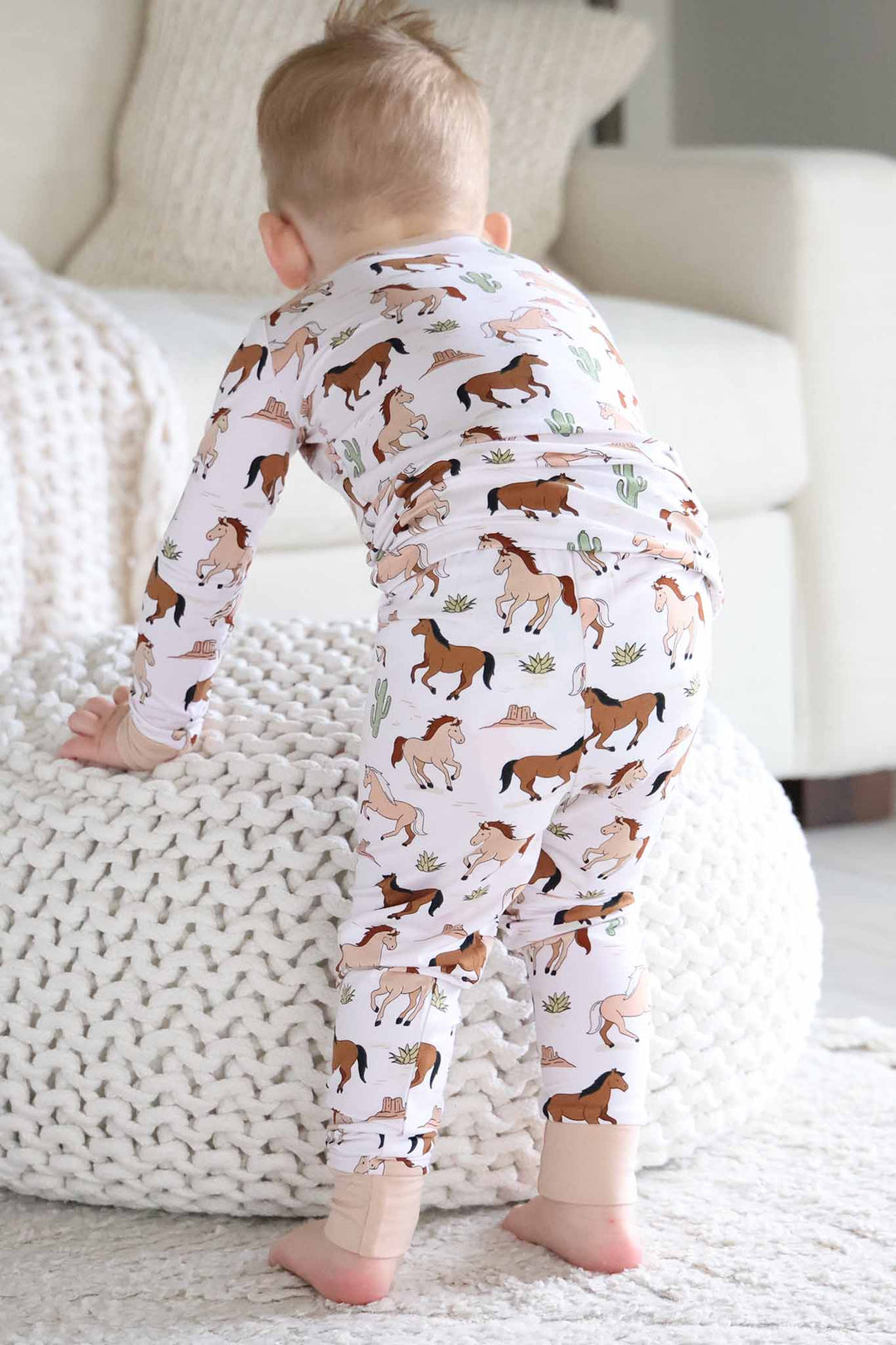 boy leaning over ottoman in pony club neutral two piece pajama set 