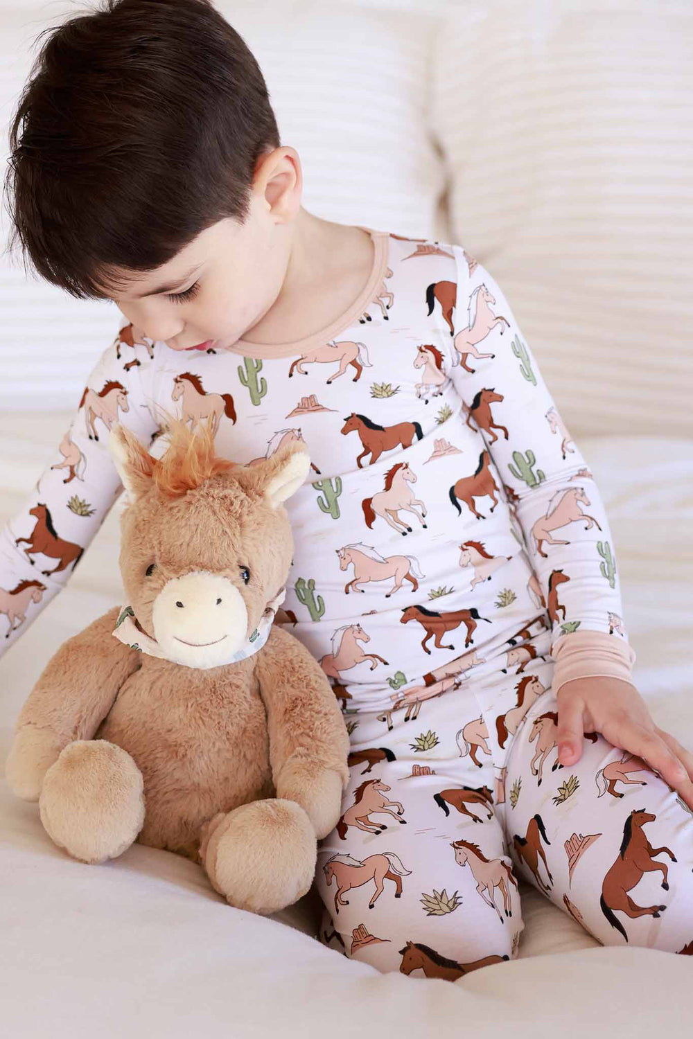 boy in pony club pajamas with peanut pony stuffed animal