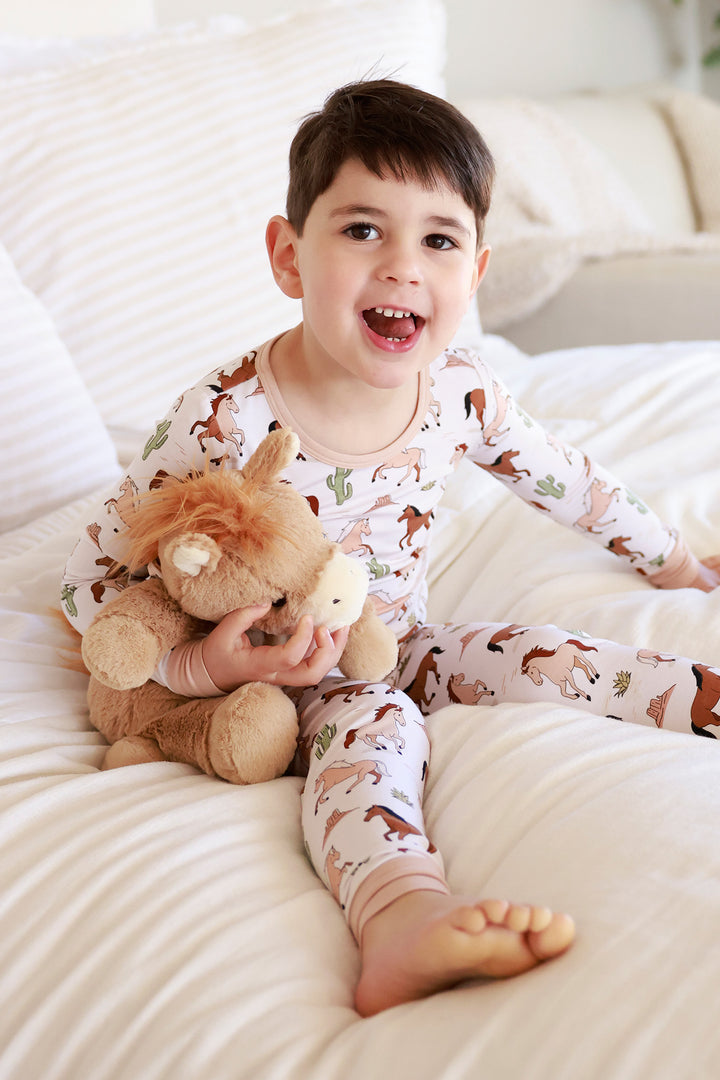 boy sitting on bed with his tongue out holding horse stuffed animal