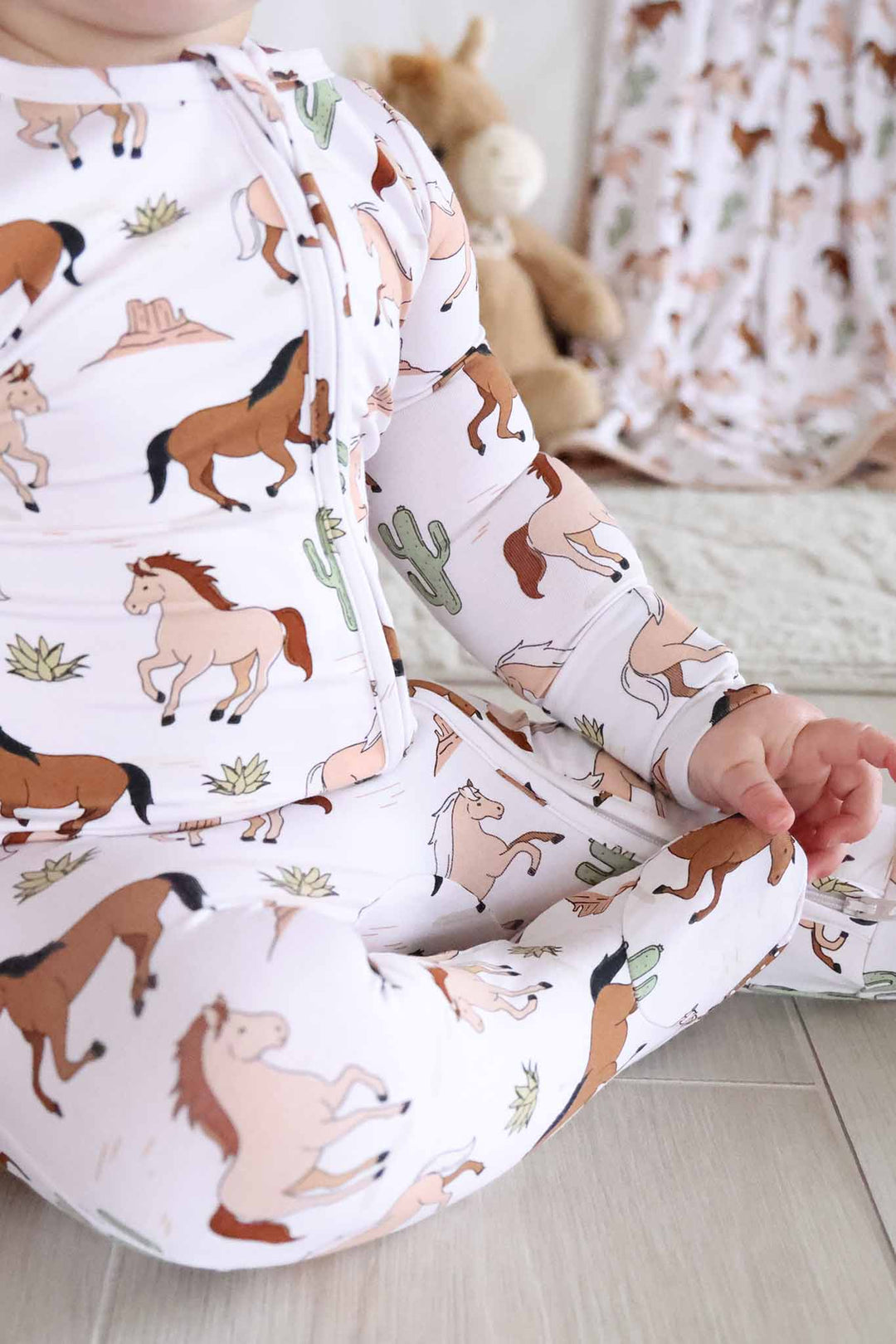 neutral pony club zipper footie with horses and cacti