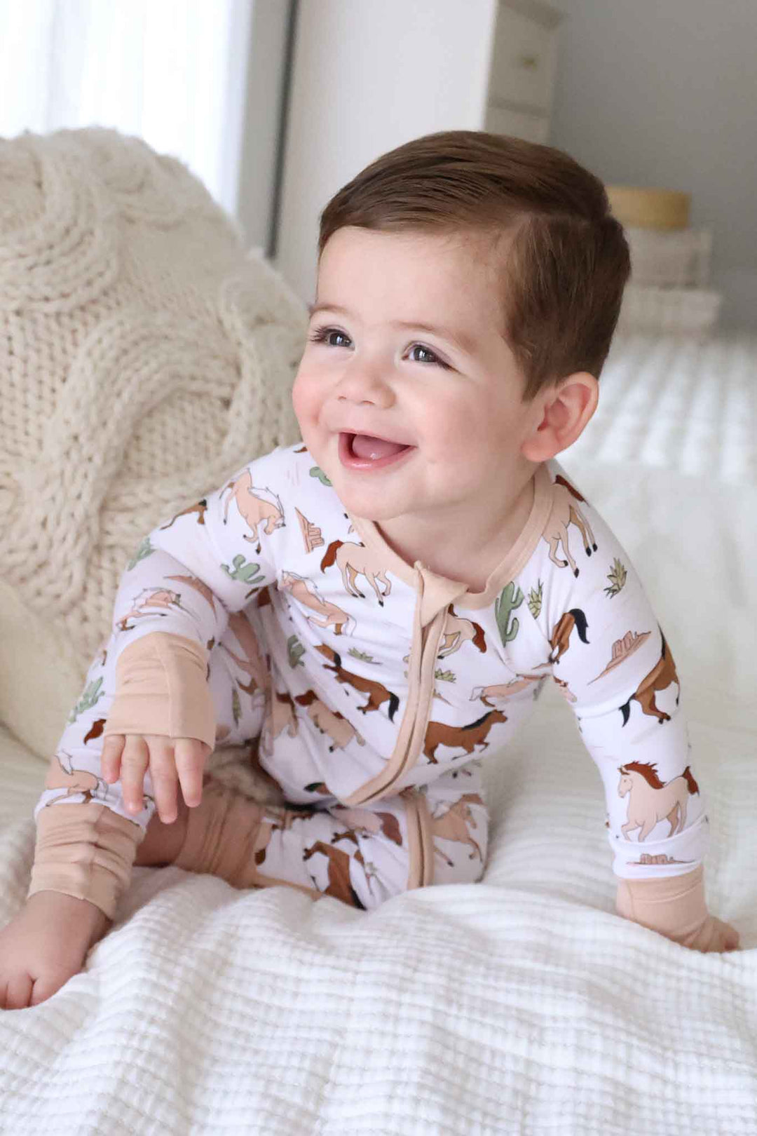 smiling baby boy in pony club neutral convertible zip romper 