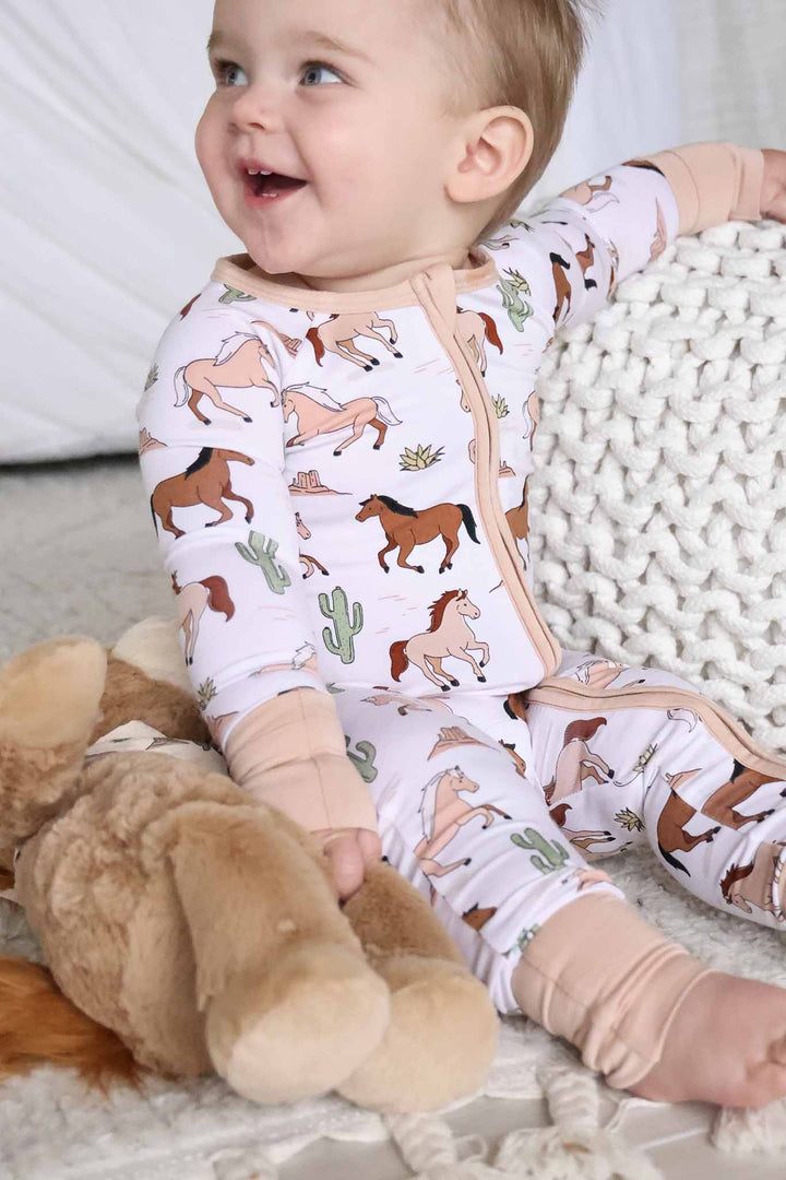 smiling baby boy sitting on ground in horse convertible zip romper 