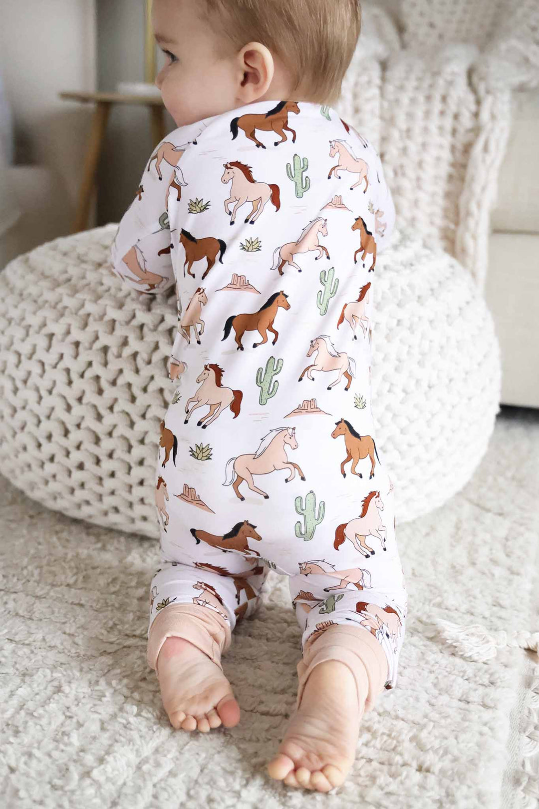 kneeling baby leaning against ottoman in pony club convertible zip romper pajama 