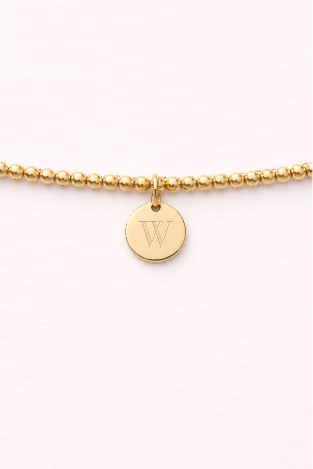 Caden Lane gold beaded bracelet close-up with engraved initial "W" disc charm