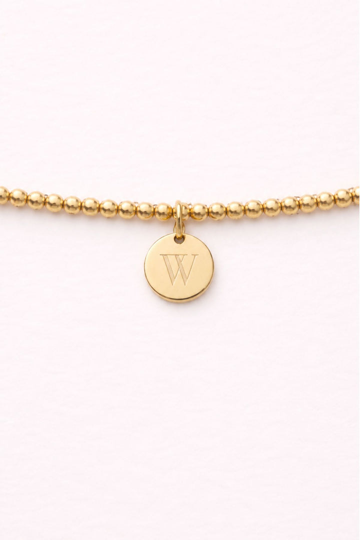 Caden Lane gold beaded bracelet close-up with engraved initial "W" disc charm
