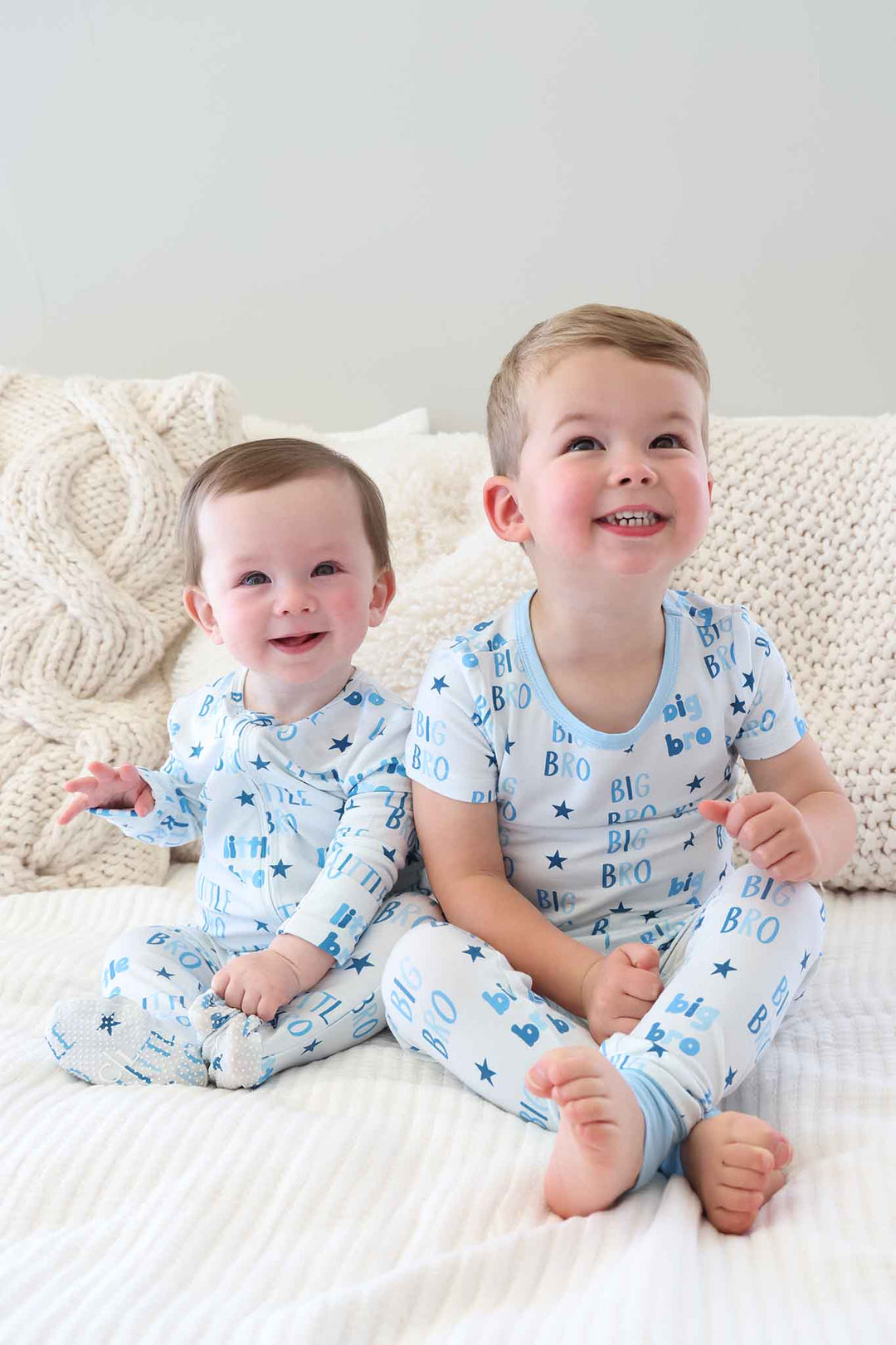 brothers sitting next to each other wearing blue star and block letter big bro and little bro pajamas 