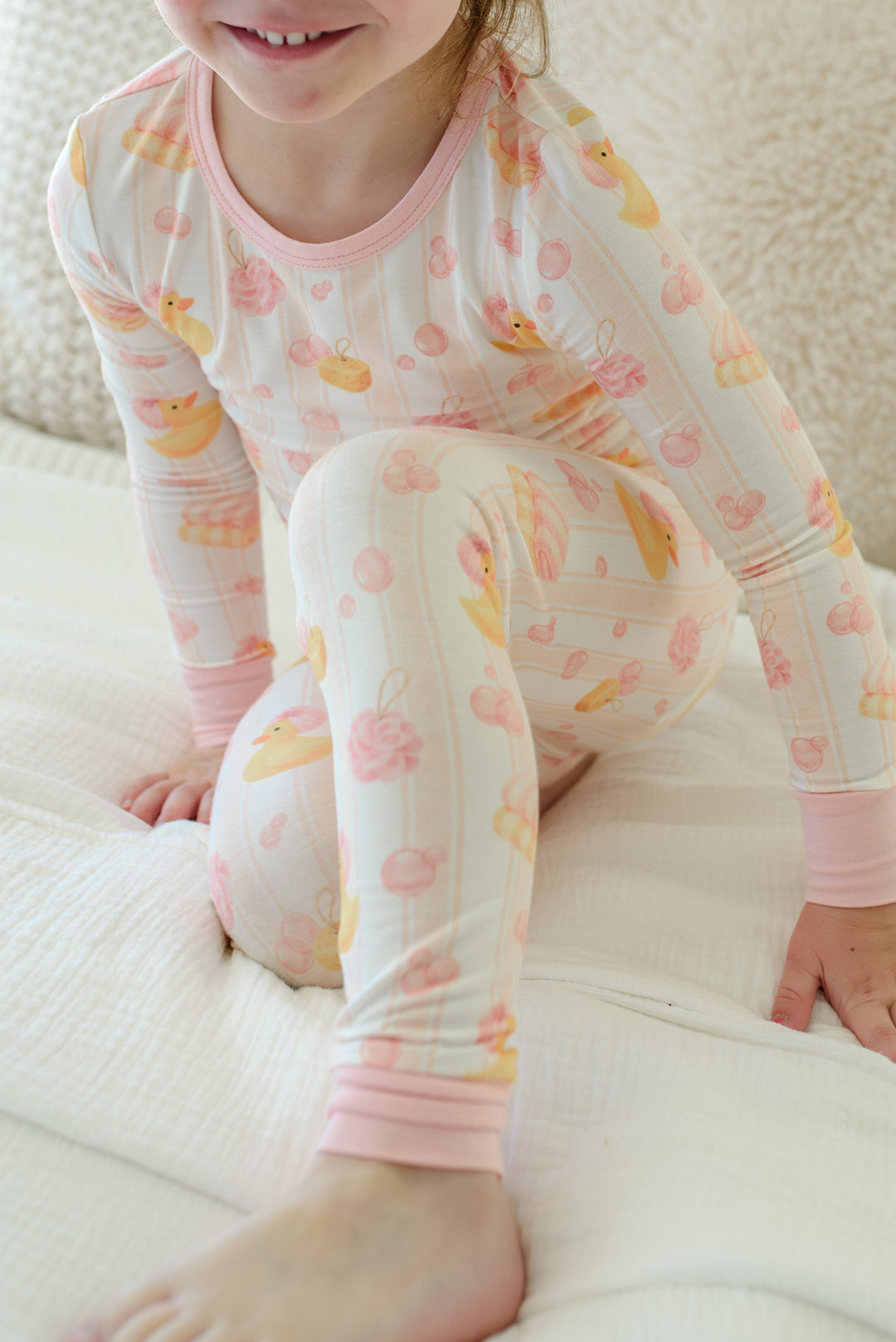 Detail shot of pink Bubble Duckies two-piece bamboo pajama set showing ribbed pink cuffs and yellow duck print fabric