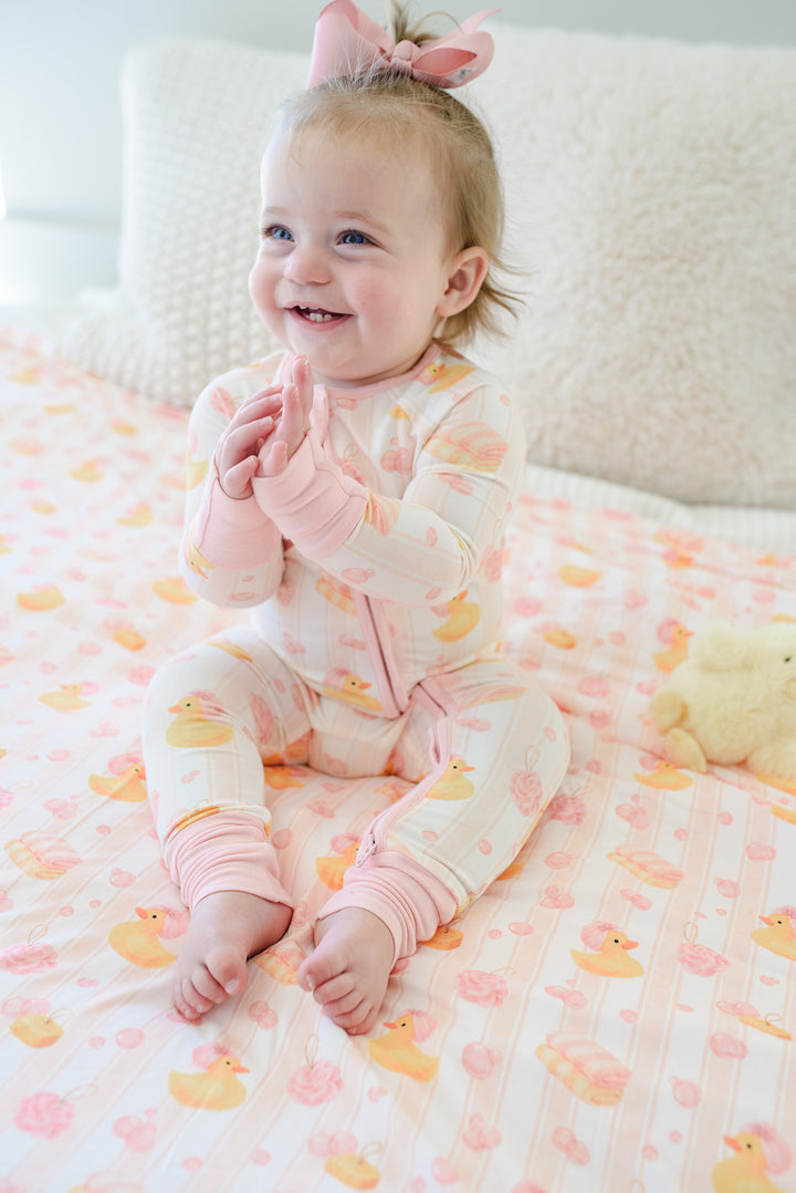 Baby wearing pink Bubble Duckies convertible zip romper showing rubber duck print detail from above