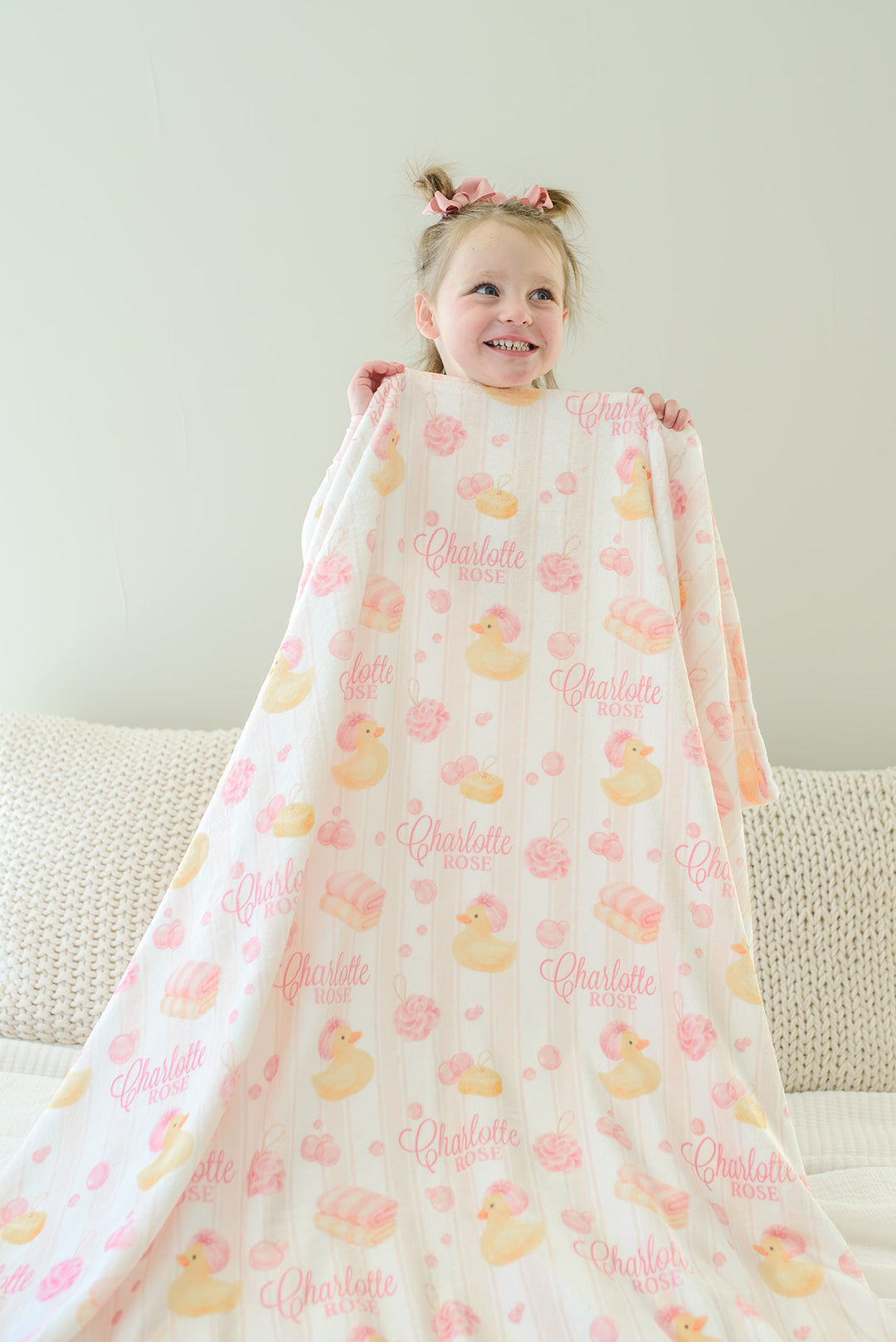Child peering over pink Bubble Duckies personalized blanket with yellow rubber duck and pink rose print