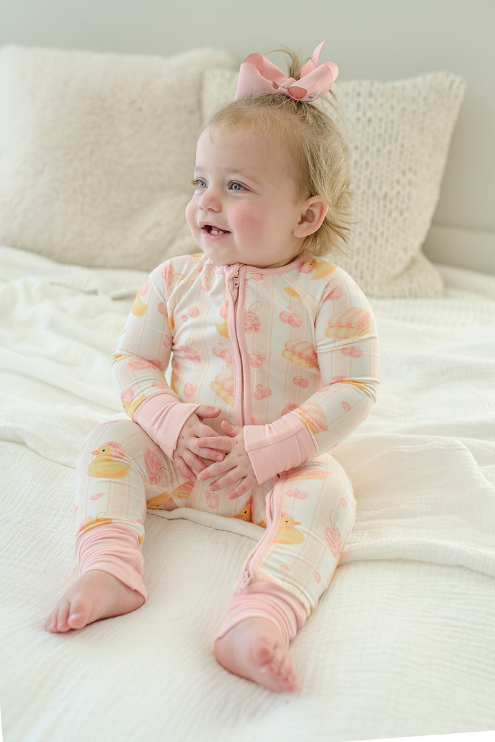 Pink Bubble Duckies convertible zip romper lifestyle shot with baby girl in matching duck print setting