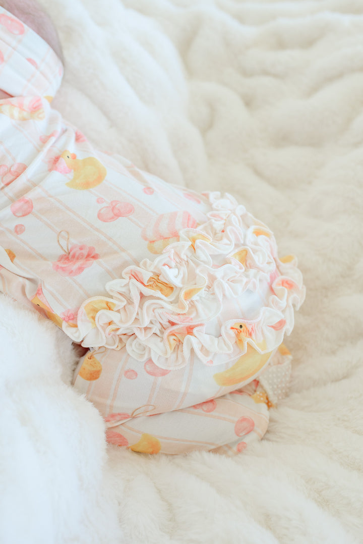 Close-up of fluffy ruffle bottom on pink Bubble Duckies bamboo zipper footie pajamas with yellow duck print