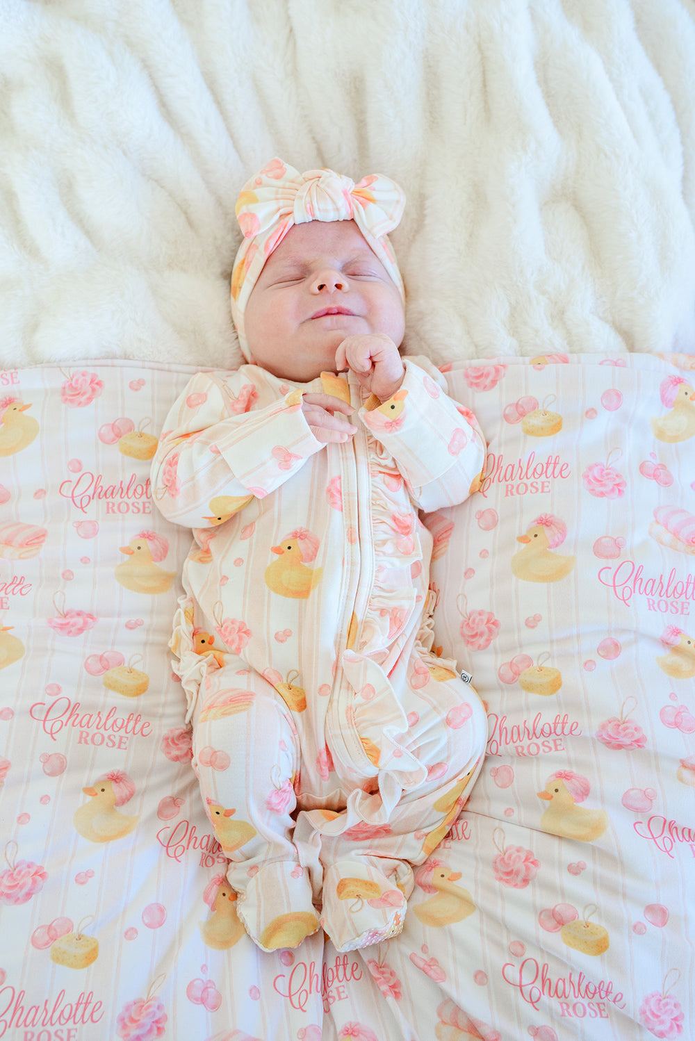 girl laying on pink personalized rubber duckie swaddle blanket