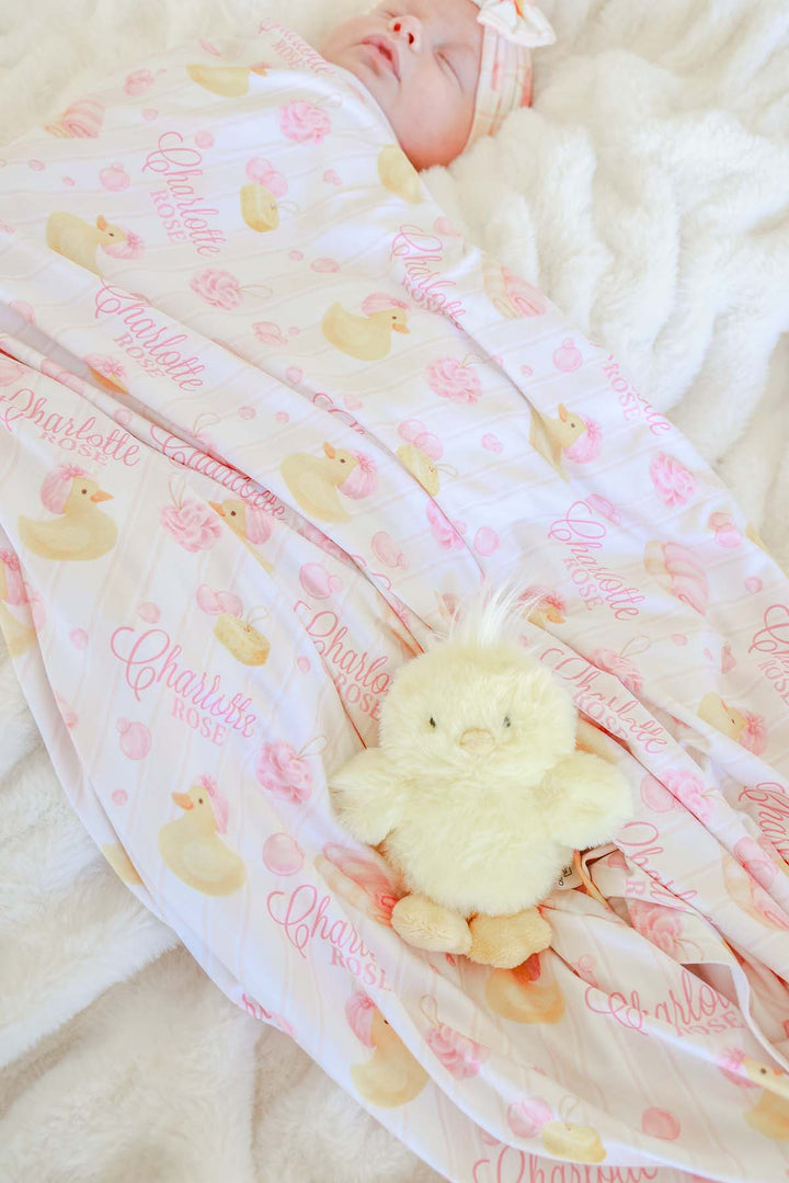 closeup of pink bubble duckies personalized swaddle blanket with duck stuffed animal 