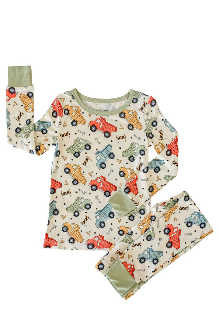 Flat lay of a Caden Lane cream knit two-piece pajama set in a Busy Builder print featuring dump trucks, cones, and wrenches, with sage neckline and cuffs.