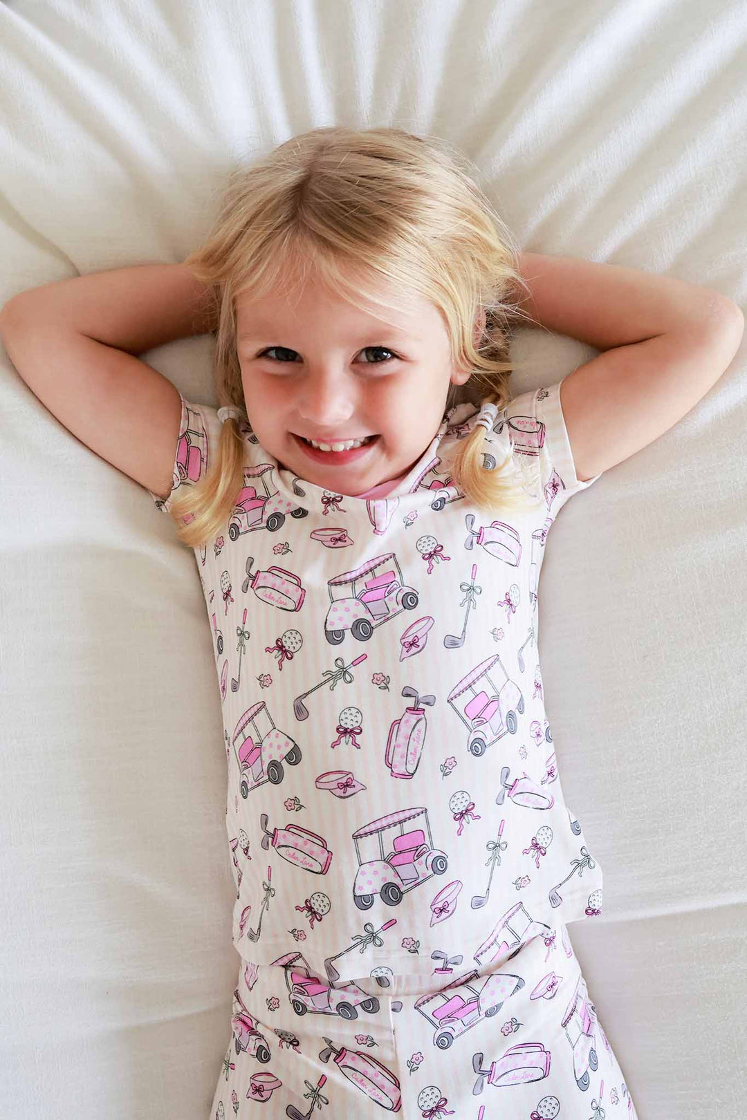 girl laying on bed in caddie crew pink 2pc pajama set