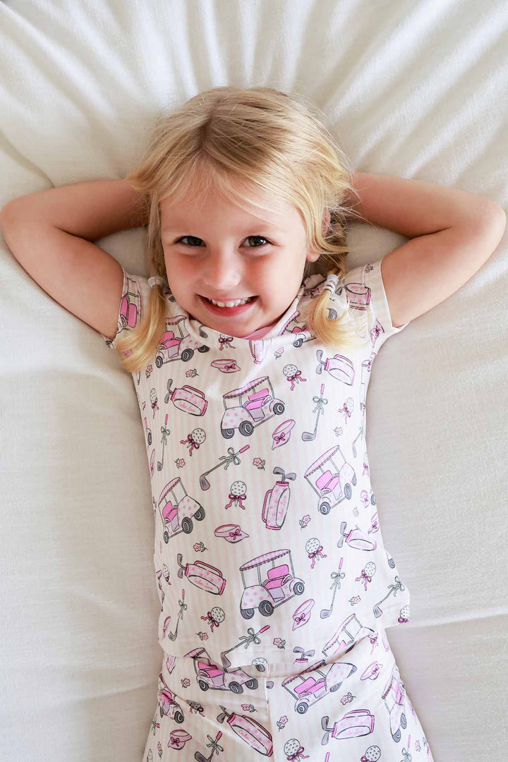 girl laying on bed in caddie crew pink 2pc pajama set