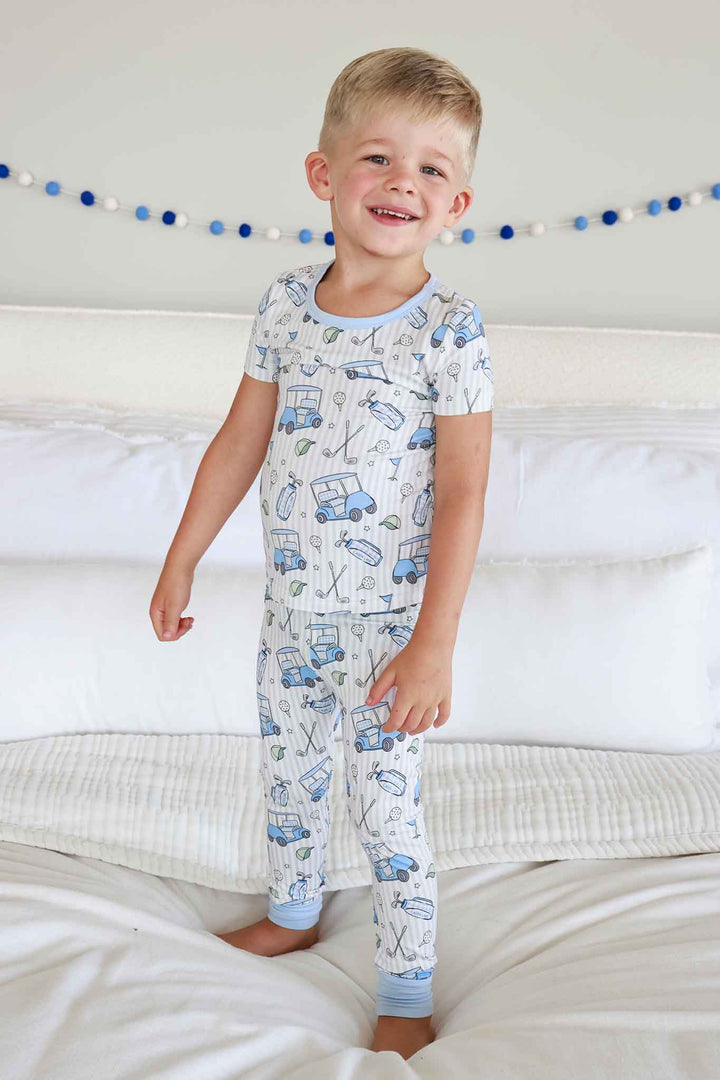 boy standing on bed in caddie crew boy two piece pajama set