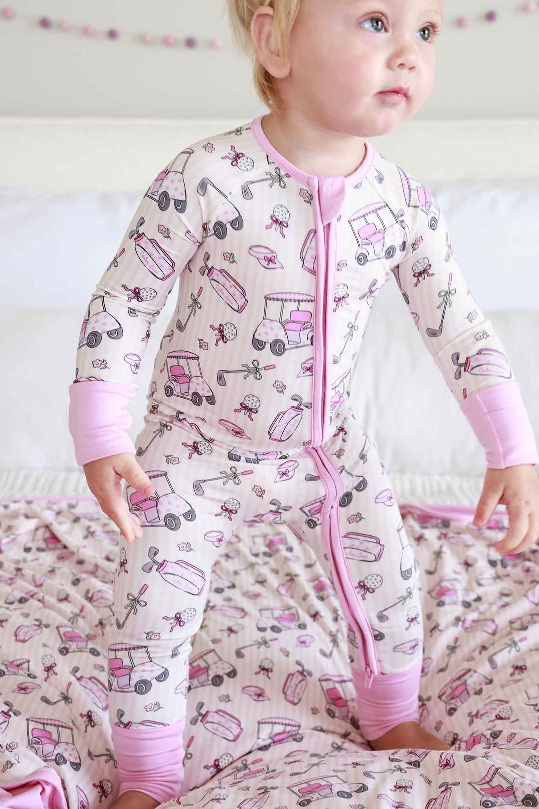 girl standing on bed in caddie crew pink convertible zip romper