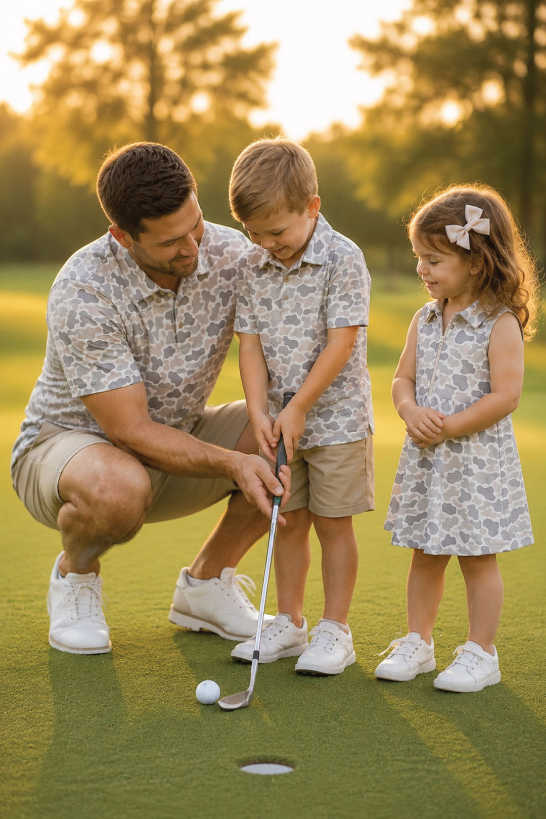 Dad wearing the Camo Cutie Short Sleeve Polo and matching son with the kids polo and daughter wearing the camo cutie polo dress