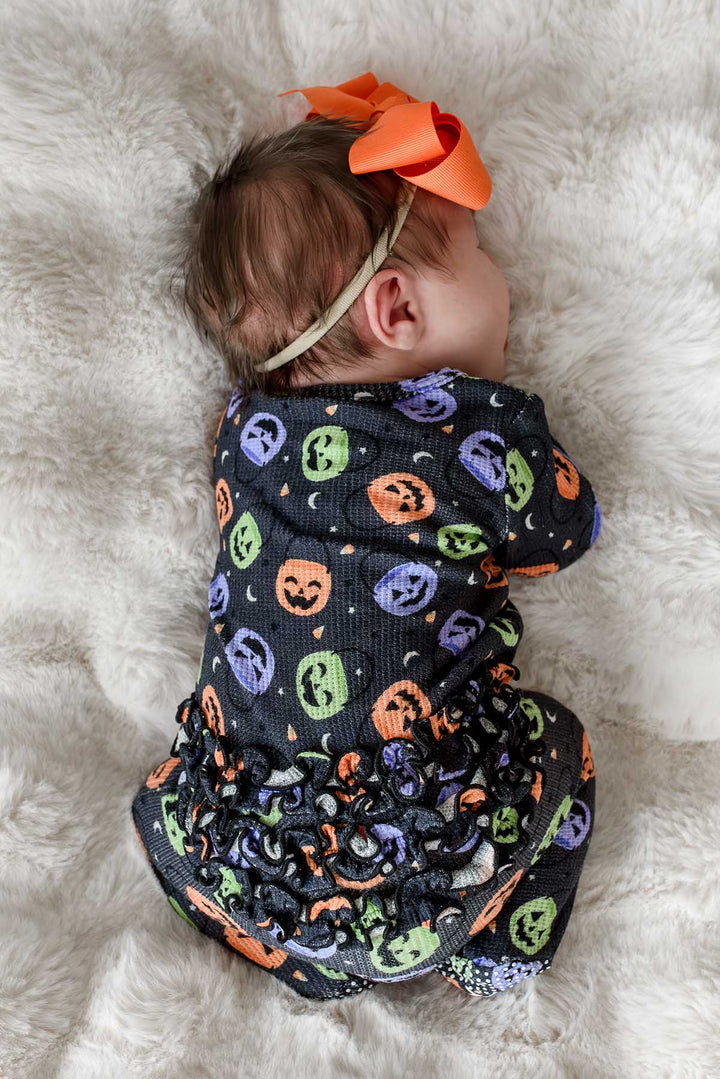 baby laying on stomach in candy crawl ruffle zipper footie with orange ribbon bow headband 