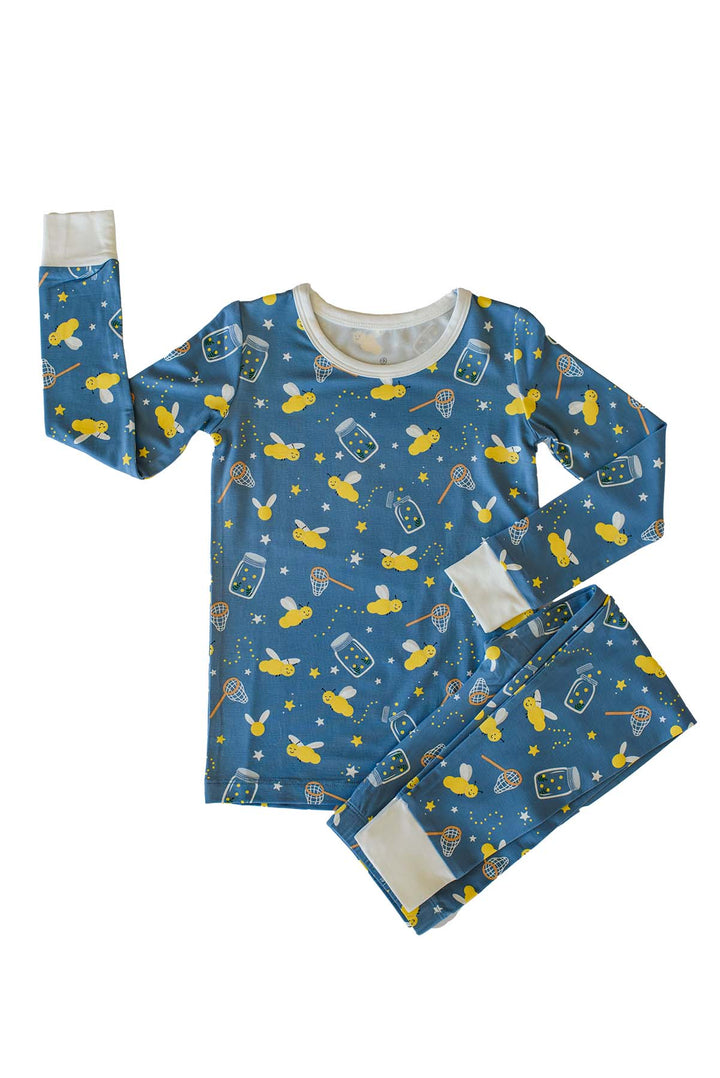 Flat lay of a Caden Lane blue two-piece bamboo pajama set in a Chasing Fireflies print featuring fireflies and mason jars, with one sleeve outstretched and cream cuffs.