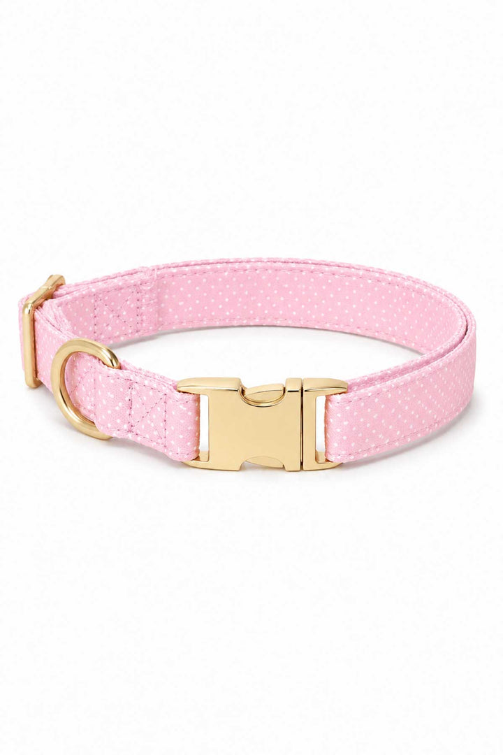Pink polka dot dog collar with gold quick-release buckle and D-ring on a white background