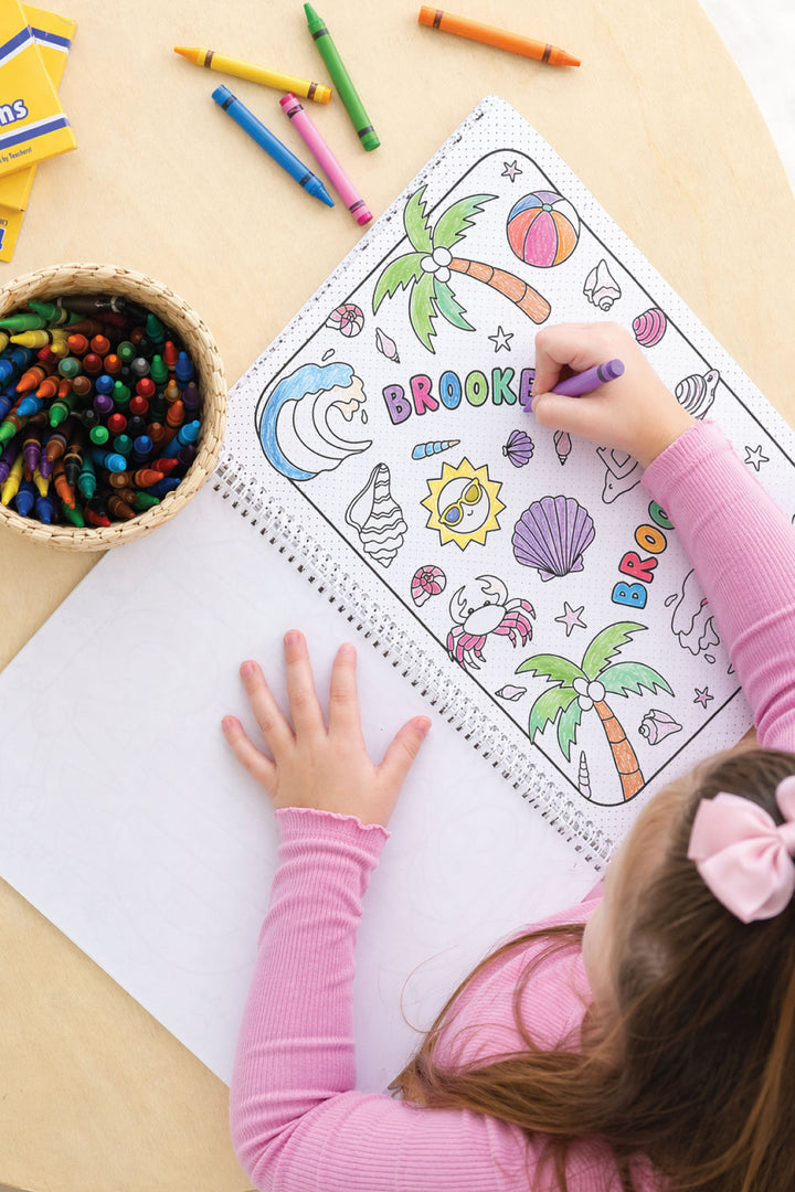 girl coloring beach themed coloring book with crayons 