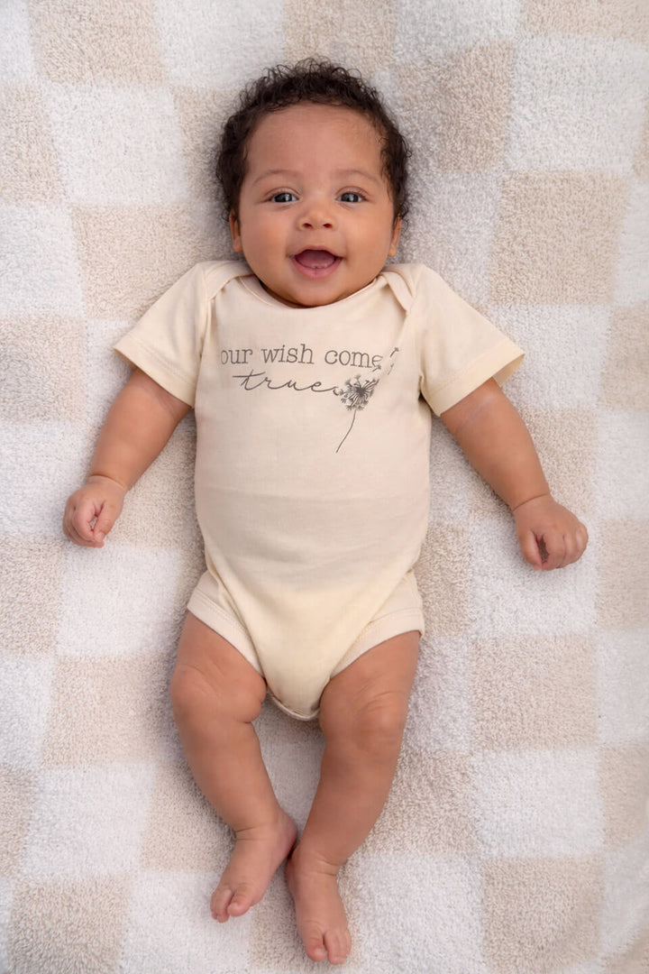 baby wearing our wish come true graphic cotton bodysuit in natural, conceive fertility foundation
