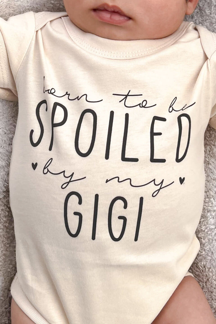 close up of personalized born to be spoiled graphic on natural cotton baby bodysuit